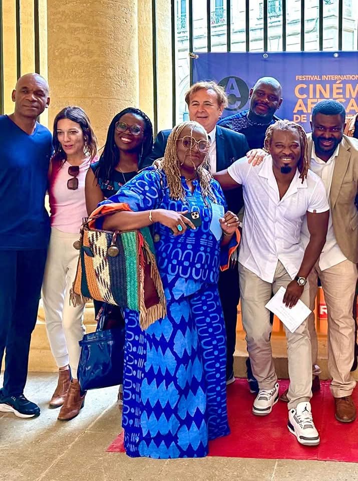 Photo de groupe des invités et professionnels devant l'affiche du Festival Africinéma Occitanie